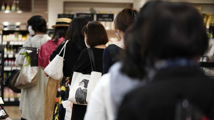 Clientes manteniendo distancia entre ellas mientras esperan en fila para pagar en una sección de alimentación de los grandes almacenes Matsuya Ginza, que reabría parcialmente el lunes, 25 de mayo de 2020, en Tokio. 