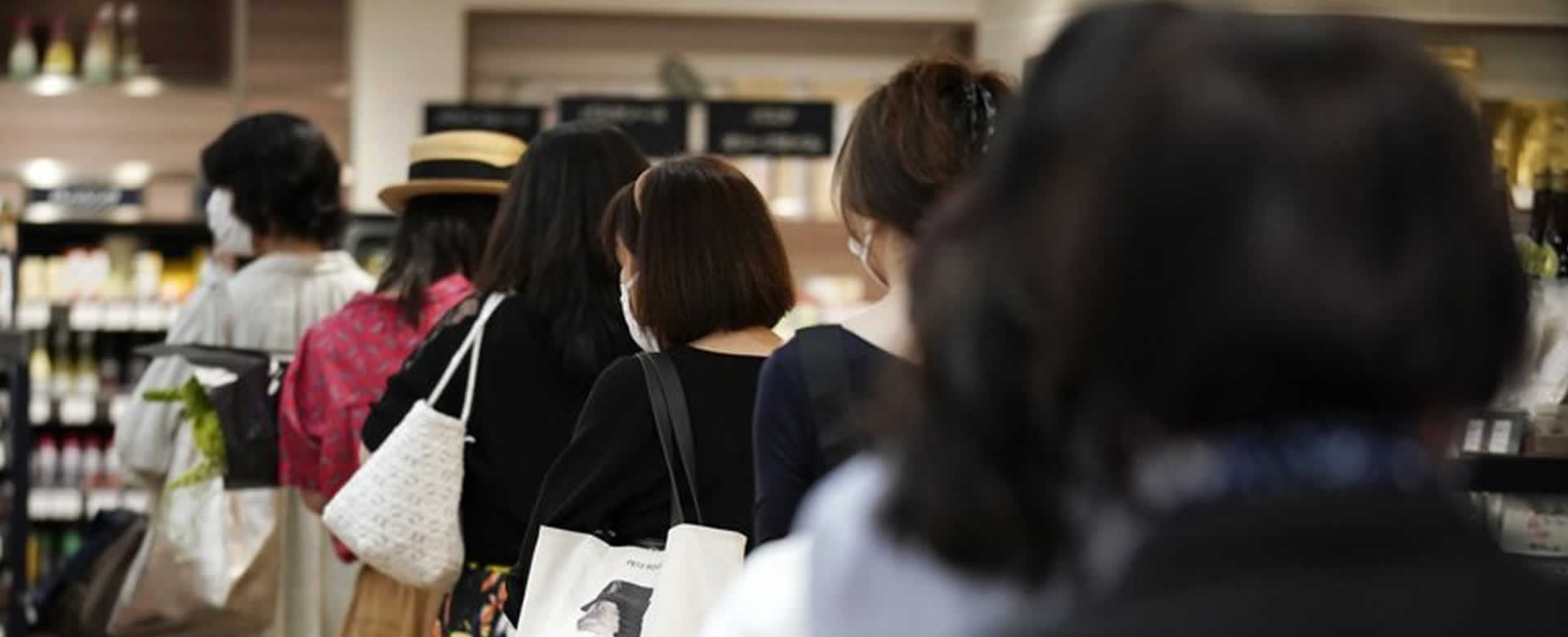 Clientes manteniendo distancia entre ellas mientras esperan en fila para pagar en una sección de alimentación de los grandes almacenes Matsuya Ginza, que reabría parcialmente el lunes, 25 de mayo de 2020, en Tokio.