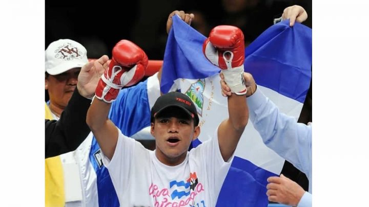 Román González levantando brazos y con la bandera de Nicaragua de fondo