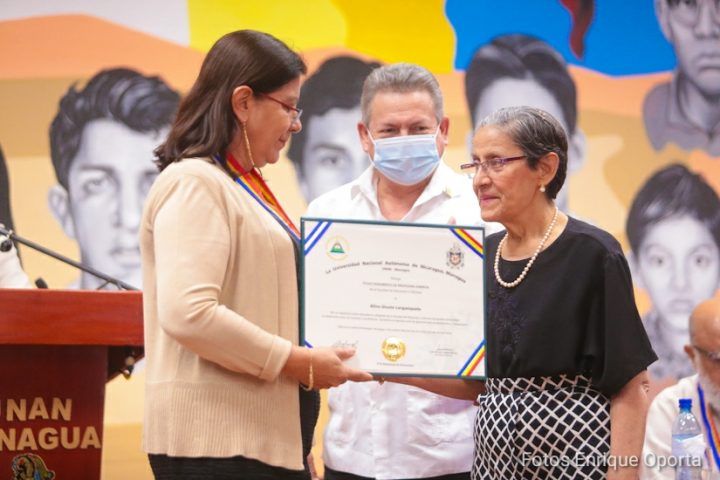 Maestra Alina Guiston recibiendo reconocimiento a manos de Ramona Rodríguez.