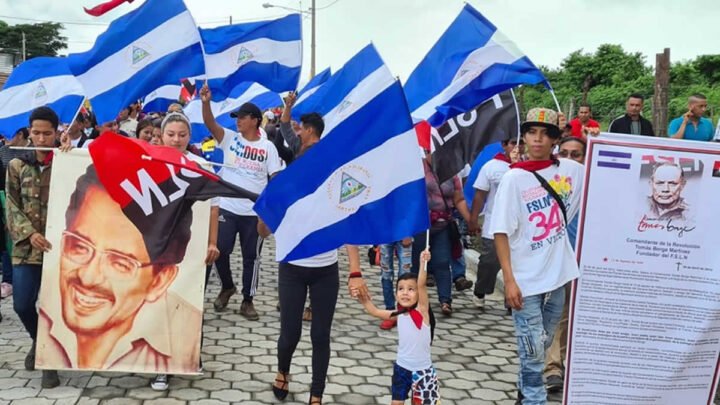 Personas alzando la bandera del FSLN y Nicaragua.