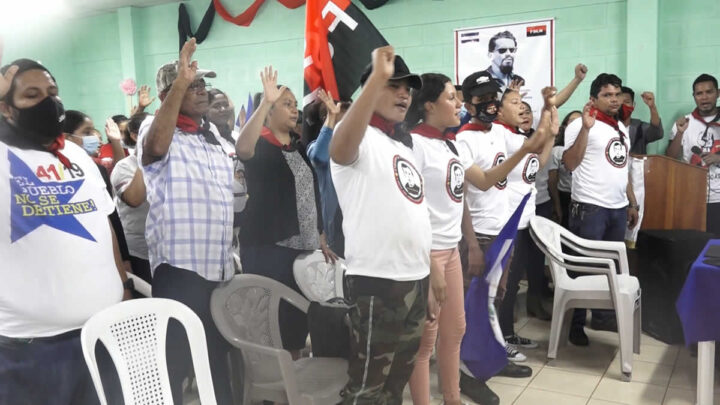 Participantes de la Unidad de Victoria Electoral levantan la mano en símbolo de lucha. 